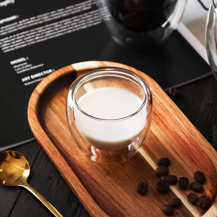 Top view of a double-wall borosilicate glass filled with milk on a wooden tray.