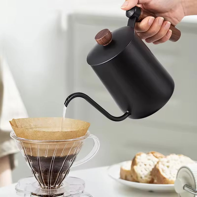 Matte black gooseneck kettle pouring water over coffee in a glass dripper.