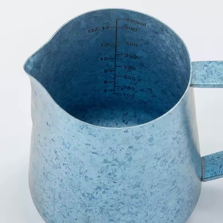 Close-up of the internal scale and pointed spout on a sky-blue titanium milk pitcher.