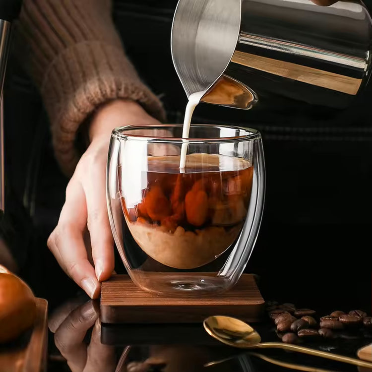 Milk being poured into coffee in a clear double-wall borosilicate glass.