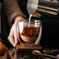 Milk being poured into coffee in a clear double-wall borosilicate glass.