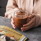 Person holding a rounded double-wall borosilicate glass filled with coffee.