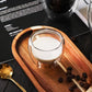 Top view of a double-wall borosilicate glass filled with milk on a wooden tray.