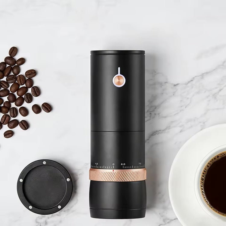 Black rechargeable electric coffee grinder beside coffee beans and a cup.